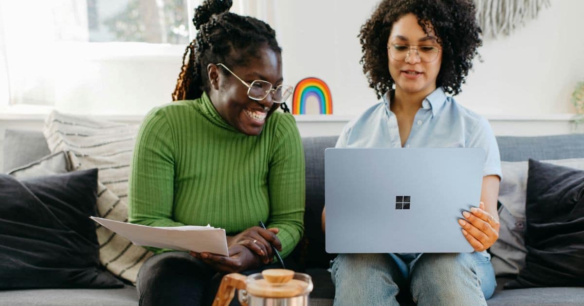 Two women at their laptop discussing their new CRM software and making sure it's as secure as possible.