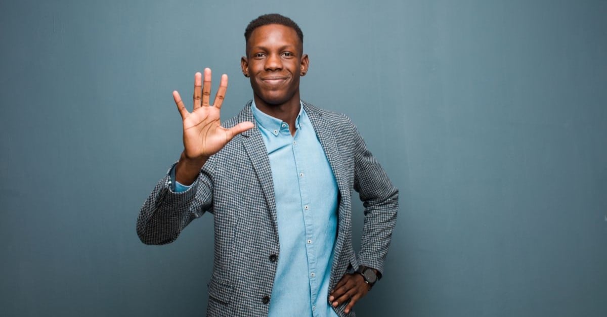 young man smiling and looking friendly, showing number five with hand forward.