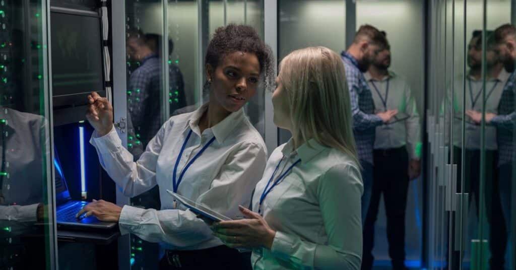 Two women are working in a data center with rows of server racks